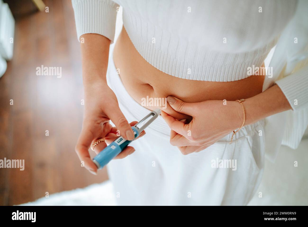 Woman injecting insulin pen in stomach at home Stock Photo