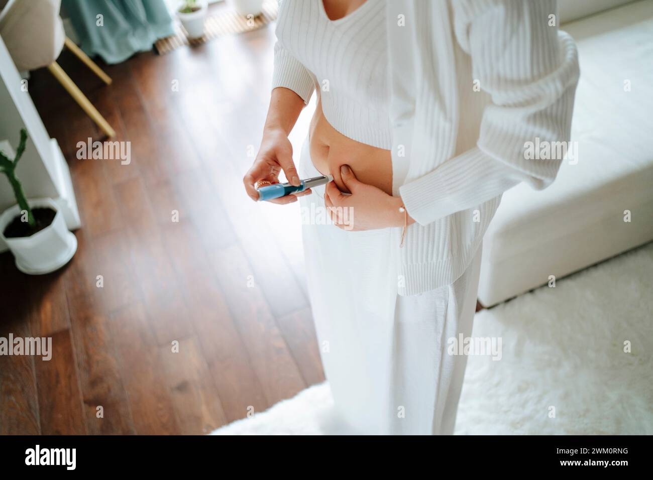Woman injecting insulin dose in stomach at home Stock Photo