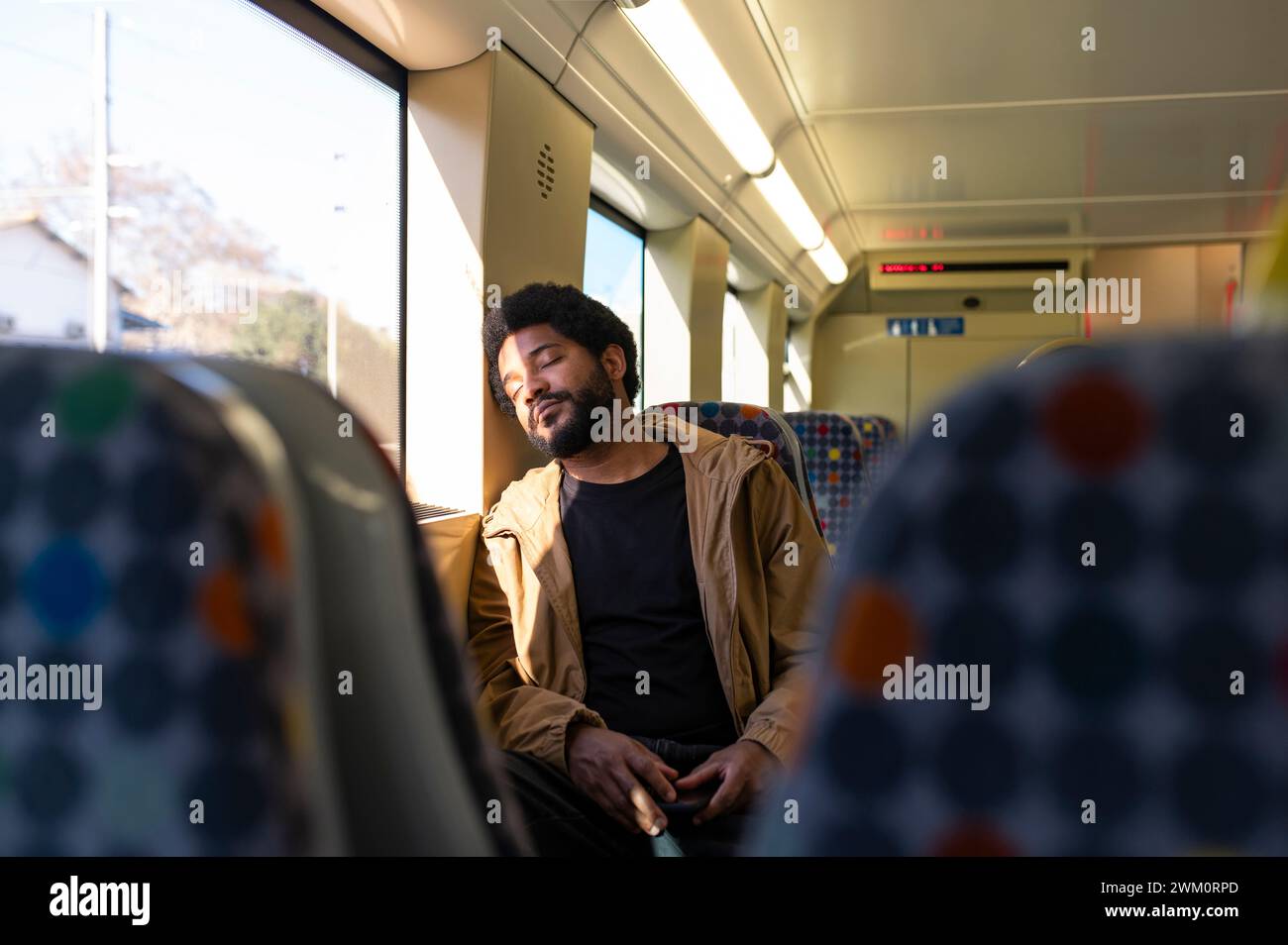 Young man napping in subway train Stock Photo