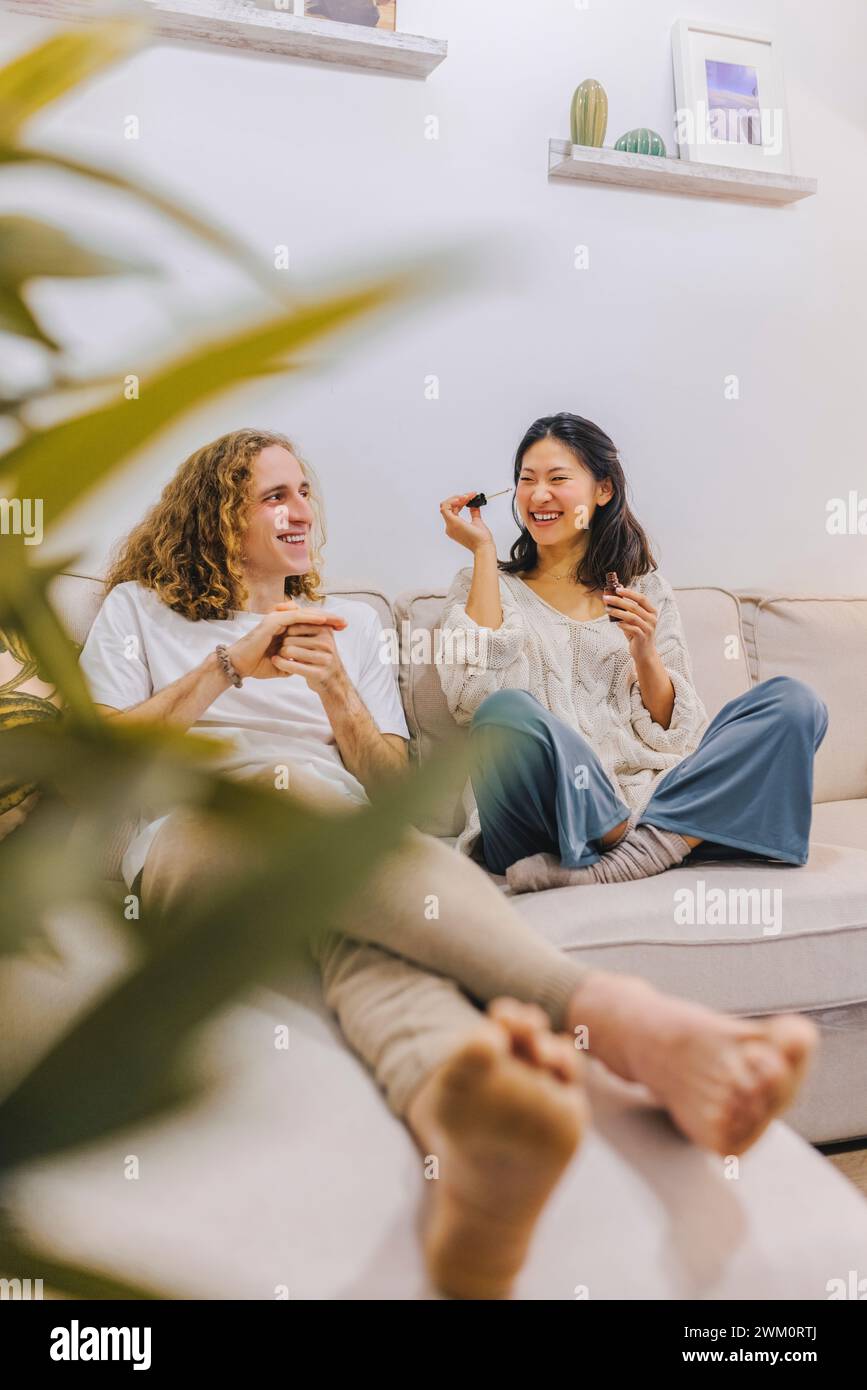 Happy couple sitting on sofa and having fun at home Stock Photo