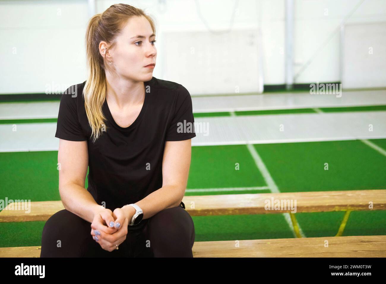 Thoughtful girl sitting on bench at gym Stock Photo - Alamy