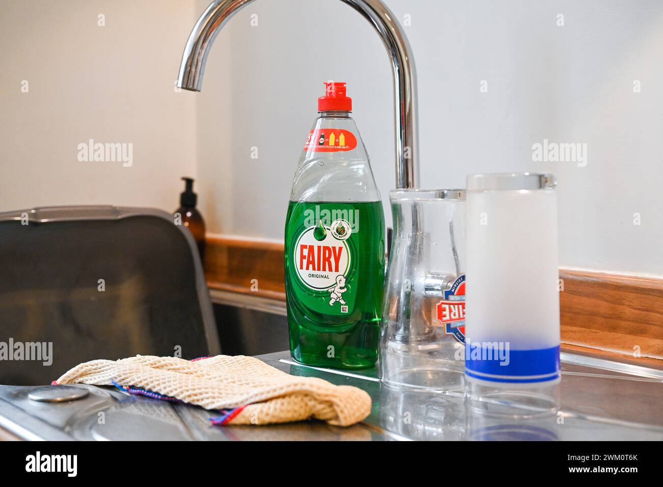 Fairy washing up liquid on a sink draining board with cups and cutlery in a UK home . Fairy is an international brand, primarily used for washing up Stock Photo