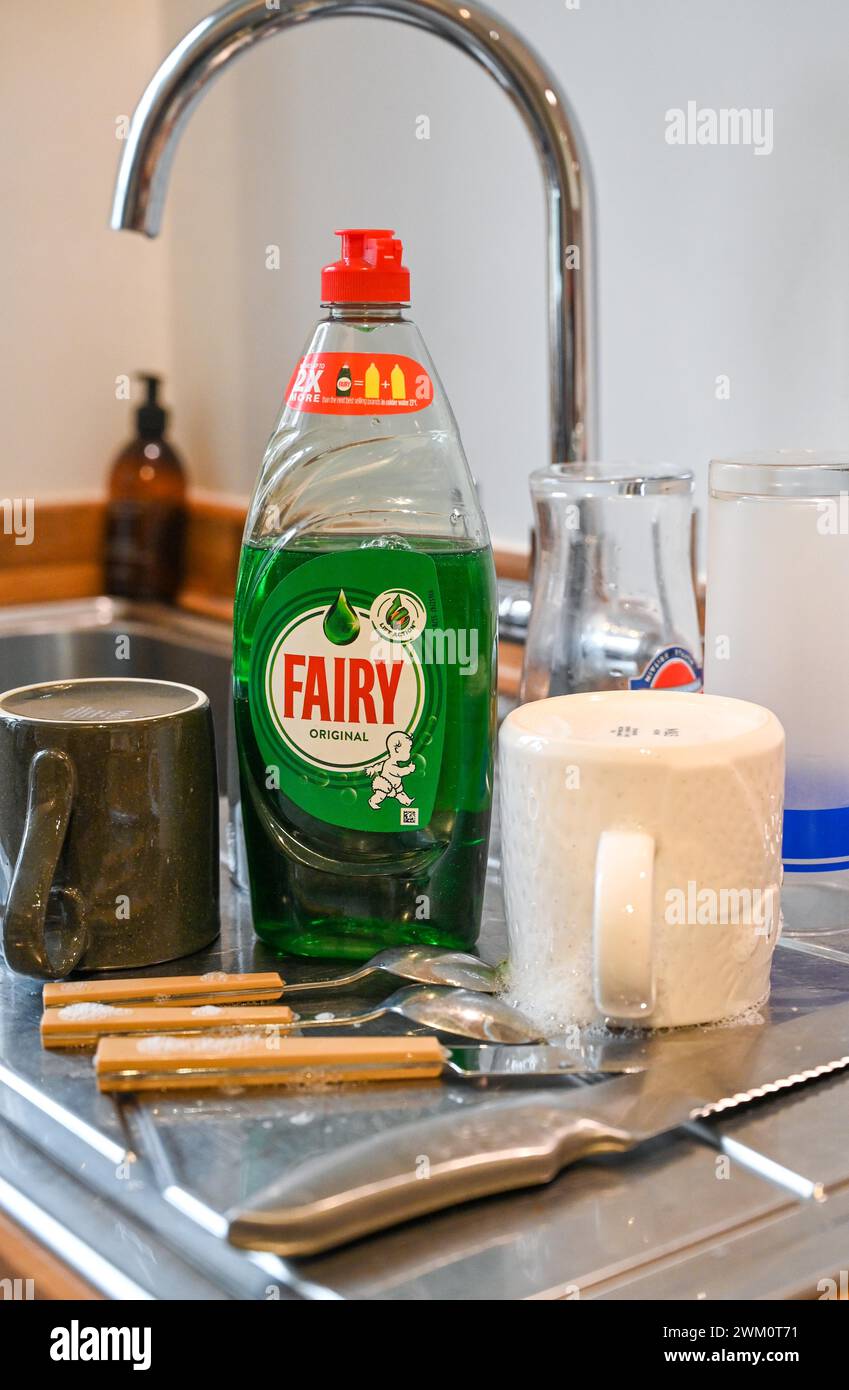 Fairy washing up liquid on a sink draining board with cups and cutlery in a UK home . Fairy is an international brand, primarily used for washing up Stock Photo