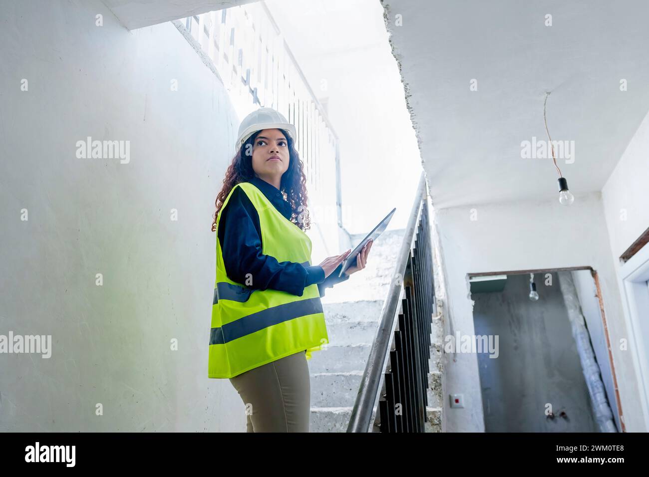 Young architect with blueprint standing on steps at construction site Stock Photo