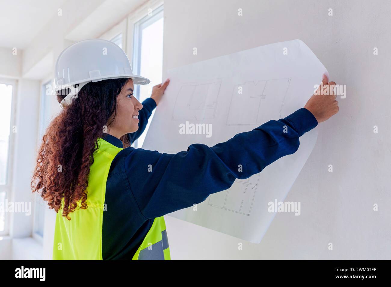 Smiling architect examining blueprint at site Stock Photo