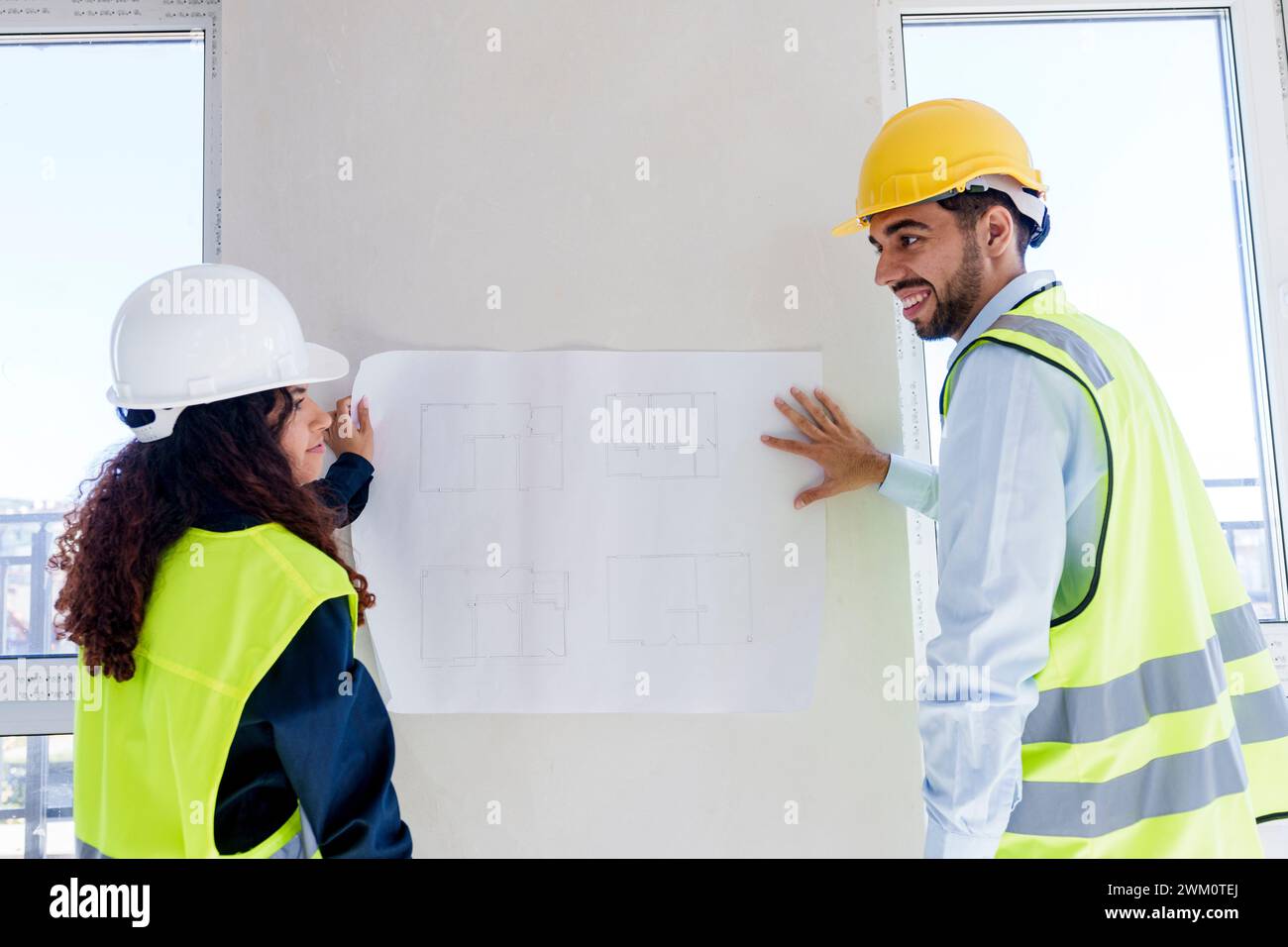 Architects discussing over blueprint on wall at site Stock Photo