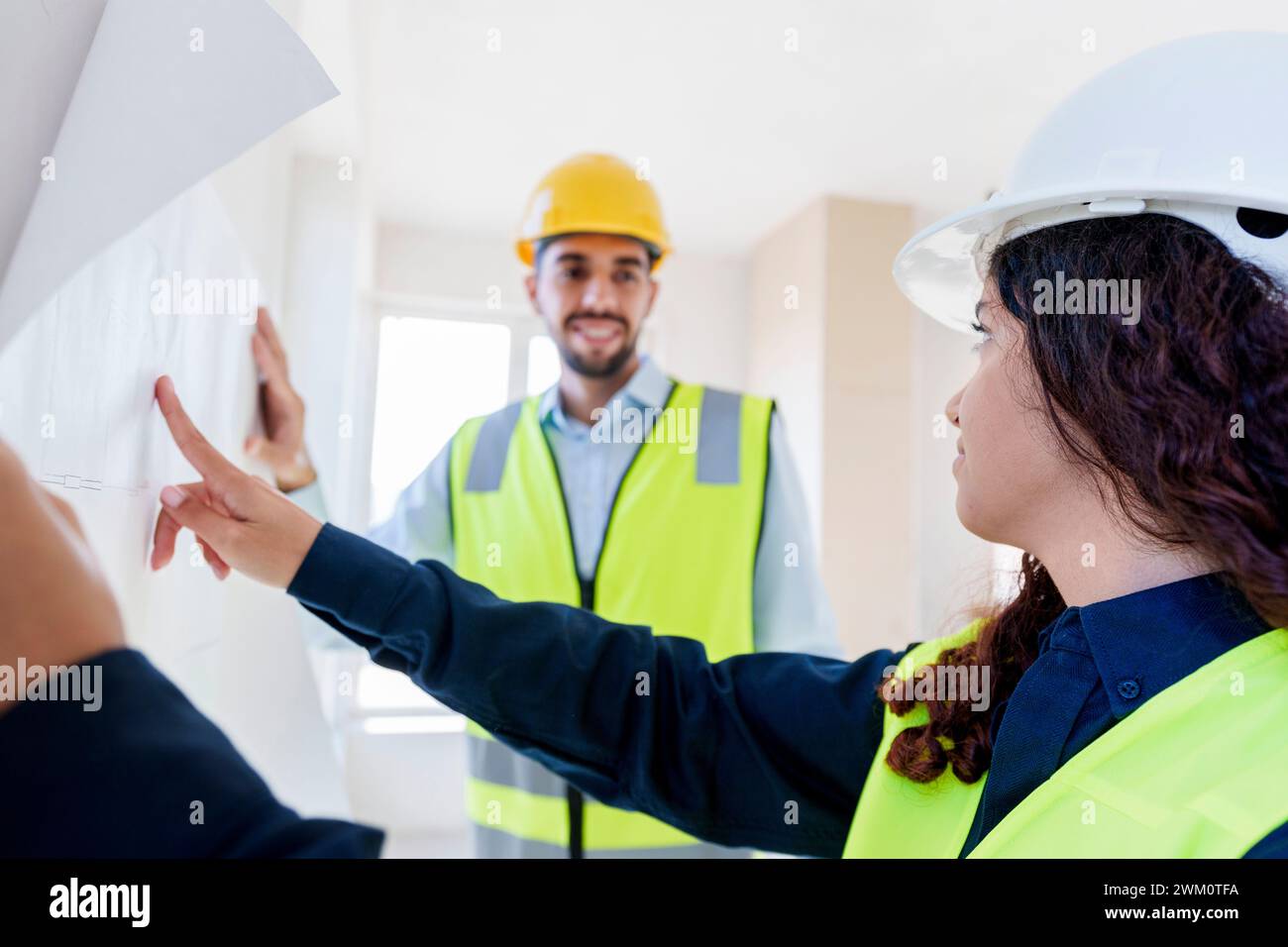 Architects discussing over blueprint at construction site Stock Photo