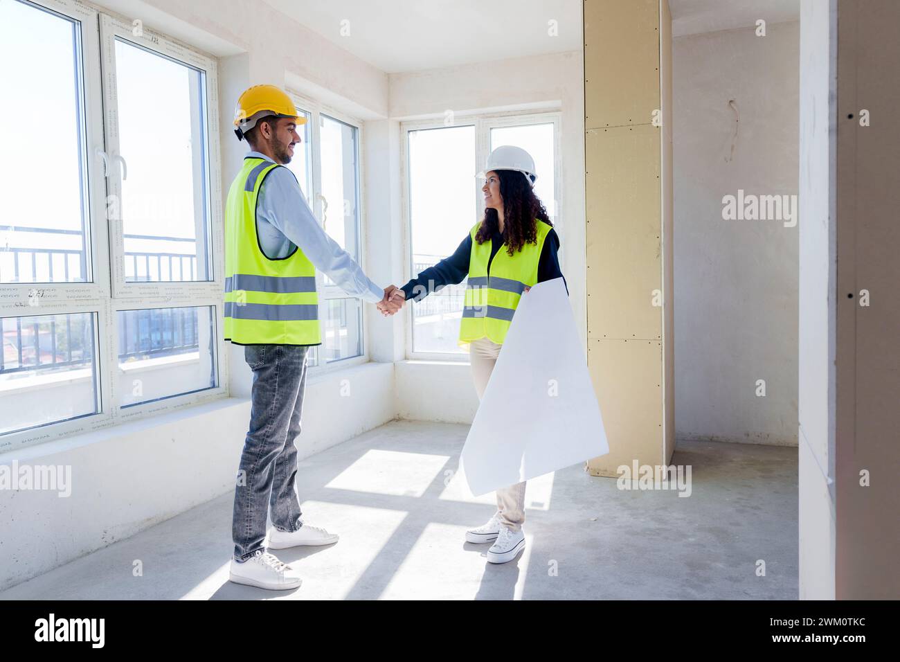 Multiracial engineers shaking hands standing at construction site Stock Photo