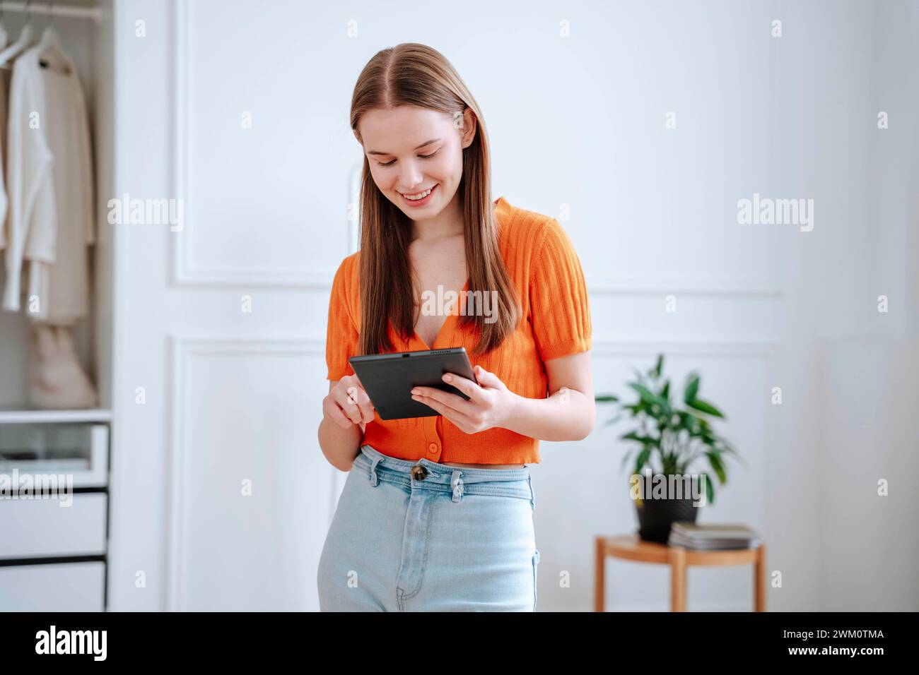 Happy young woman using tablet PC at home Stock Photo