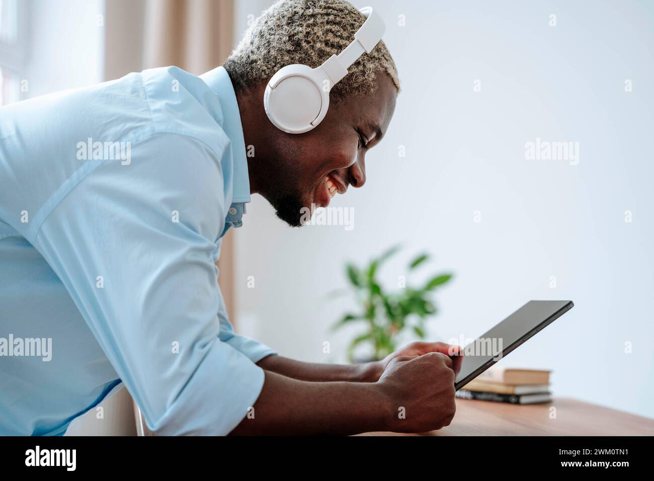 Happy man wearing wireless headphones and using tablet PC Stock Photo