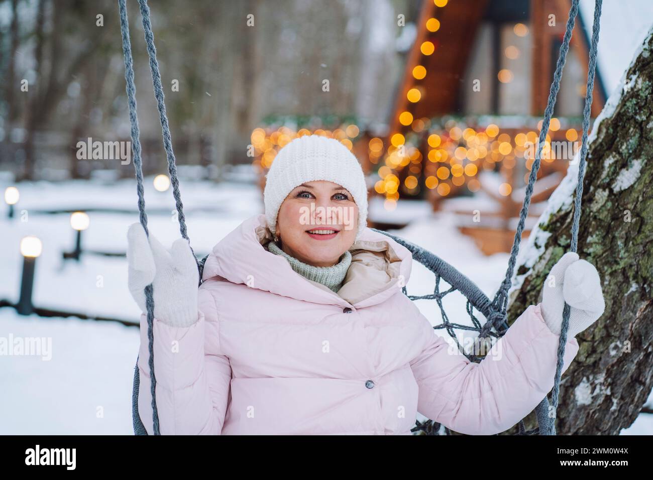 Smiling mature woman sitting on swing in winter Stock Photo - Alamy