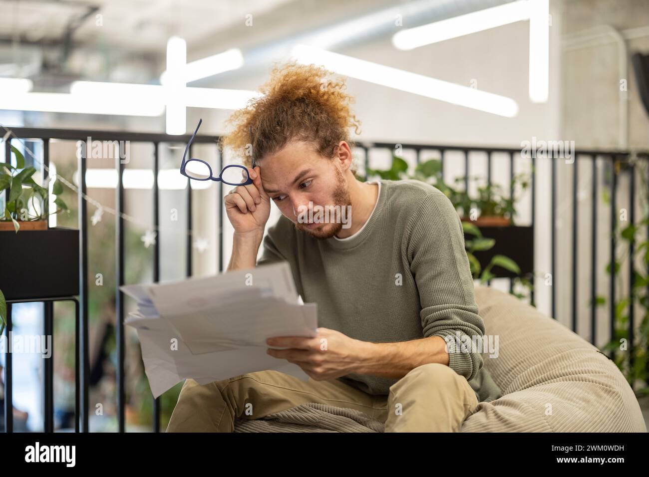 Worried businessman sitting with documents and eyeglasses at office Stock Photo
