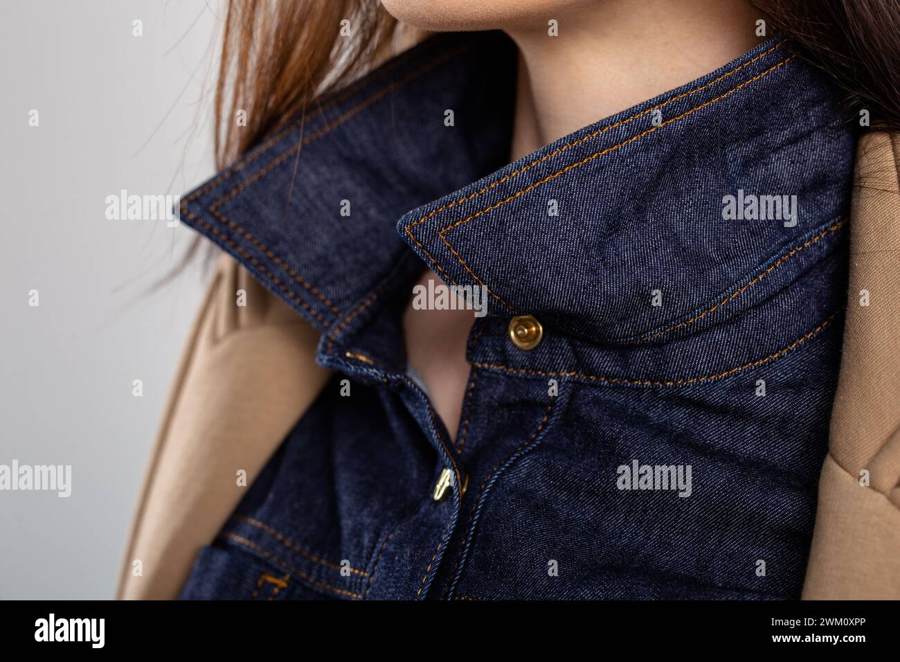 Close-up of a blue denim shirt collar with a brown corduroy jacket lapel. Shirt is buttoned up, collar turned up, and jacket open. Stock Photo