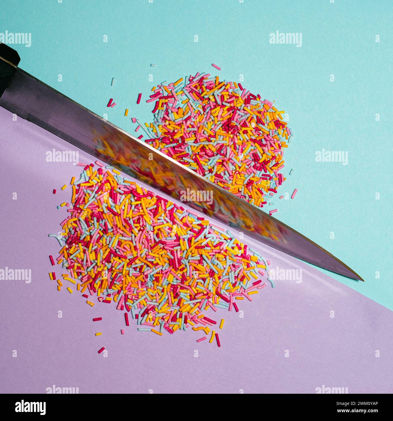 Knife cutting colorful sprinkles. Creative food concept. Flat lay. Stock Photo