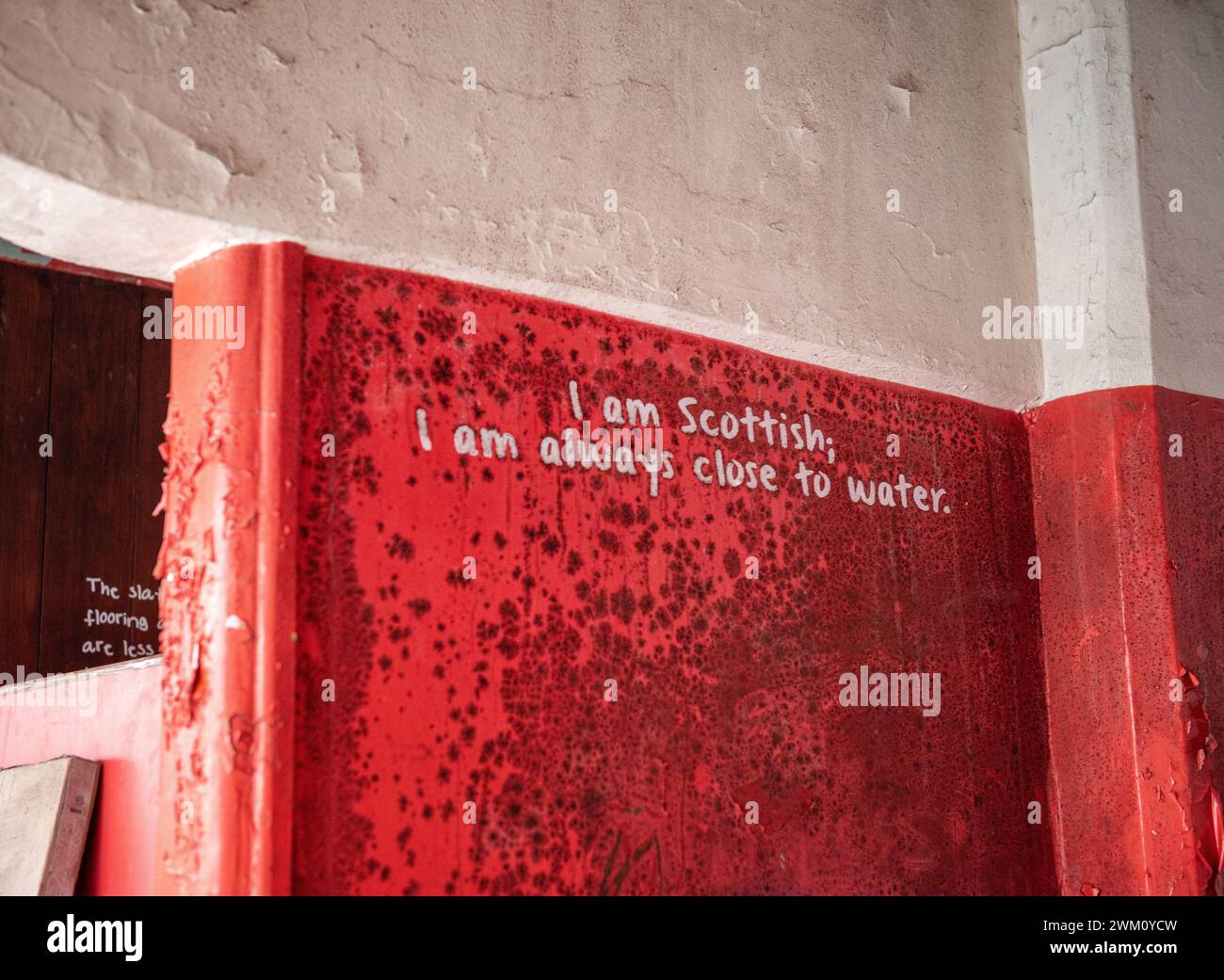 A red wall reads 'I am Scottish, I am always close to water' in the interior of Govanhill Baths swimming pool during rennovation in Glasgow 2023 Stock Photo