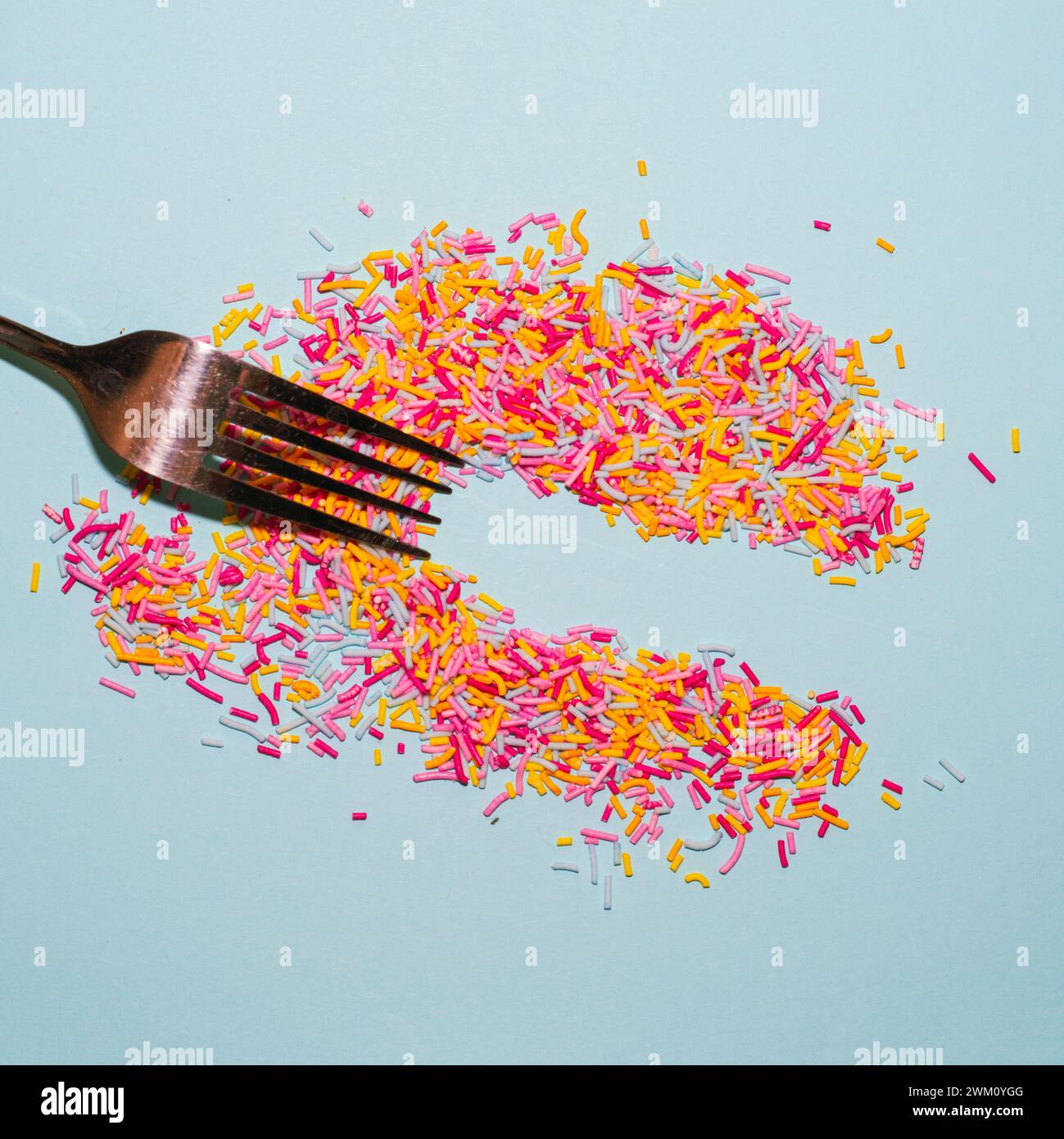 Fork spread colorful sprinkles on blue background. Creative food concept flat lay. Stock Photo