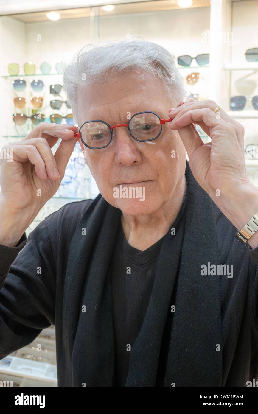 Pensioner trying on new eyeglass frames in an optical shop, 2024, New