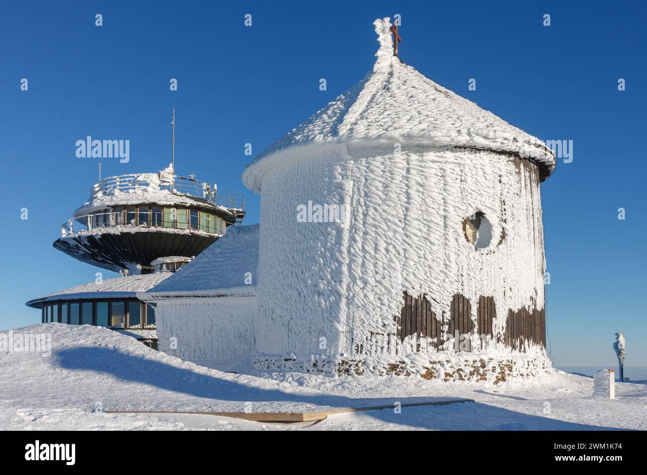 Winter morning , wooden Roman catholic chapel and disc shaped meteorological observatory in snezka, mountain on the border between Czech Republic and Stock Photo
