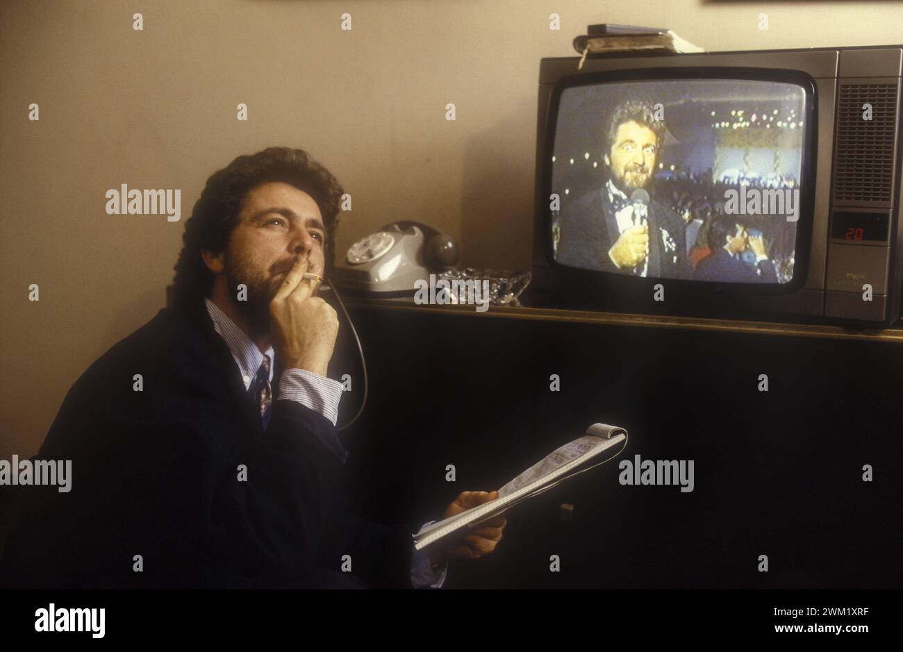 MME4743434 Italian comedian Beppe Grillo in a service flat in Rome, in front of a monitor showing his show (1988)/L'attore comico Beppe Grillo in un residence a Roma, davanti a un monitor con immagini del suo show (1988) -; (add.info.: Italian comedian Beppe Grillo in a service flat in Rome, in front of a monitor showing his show (1988)/L'attore comico Beppe Grillo in un residence a Roma, davanti a un monitor con immagini del suo show (1988) -); © Marcello Mencarini. All rights reserved 2024. Stock Photo