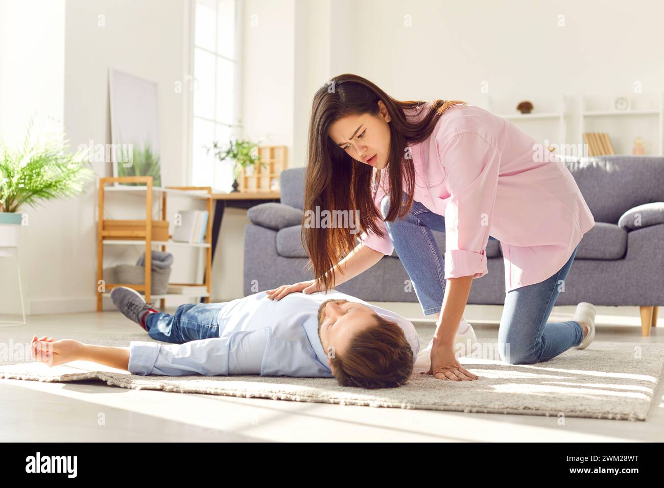 Unconscious man with heart attack lying at home with wife trying to provide first aid emergency Stock Photo