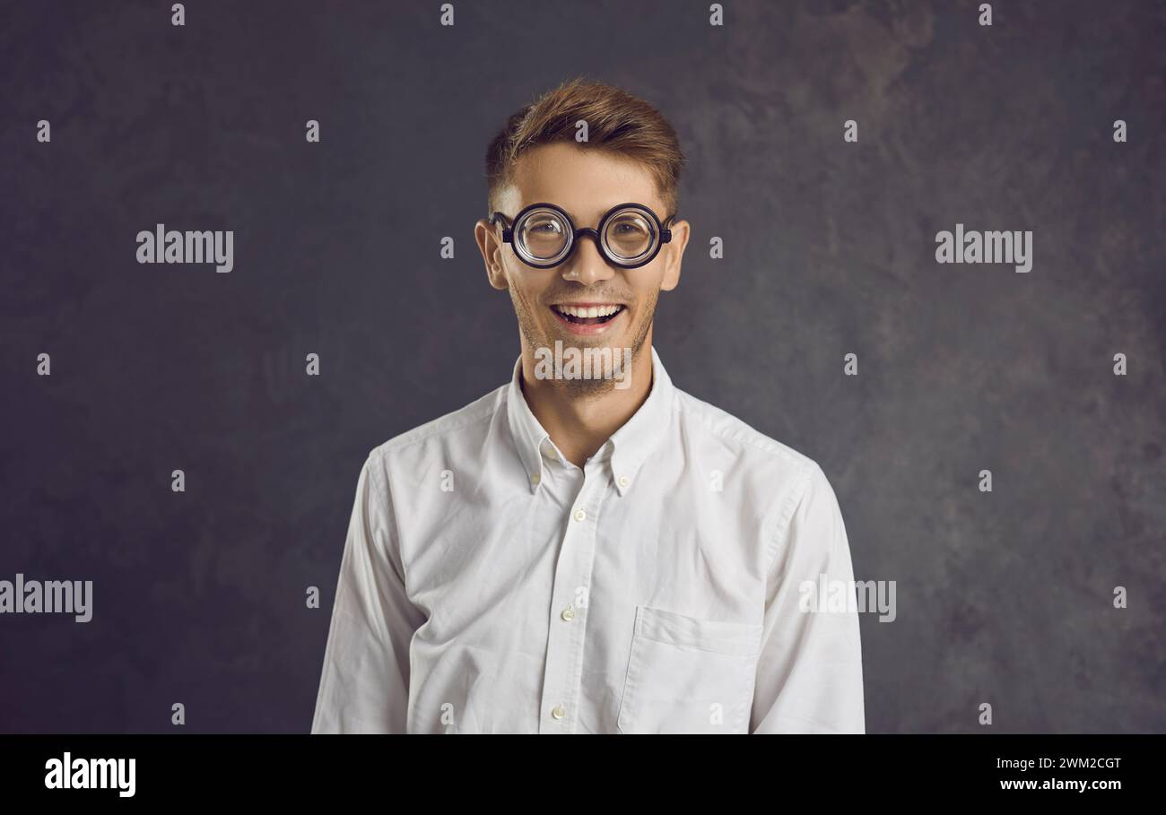 Studio portrait of cheerful young man wearing funny glasses with magnifying lenses. Stock Photo