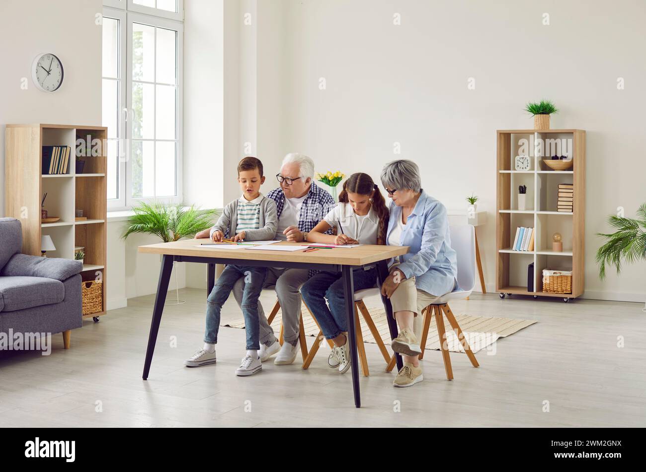 Grandparents and grandchildren spending time together, sitting at table and drawing pictures Stock Photo