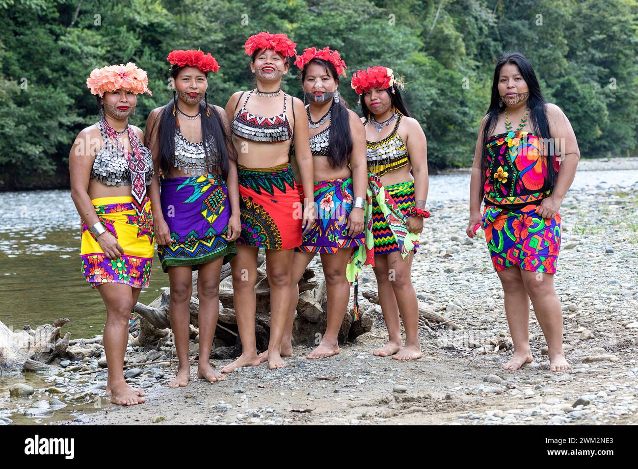 Women from Embera tribe in their traditional clothes with flowers in their heads standing close to the river and their village in the jungle, Panama Stock Photo