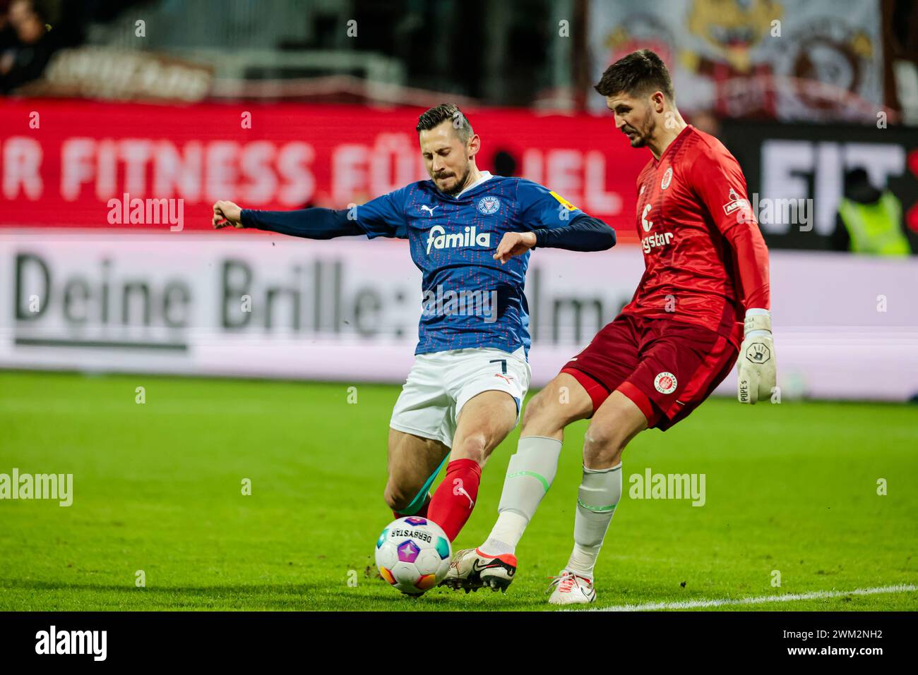 Kiel, Germany. 23rd Feb, 2024. Soccer: Bundesliga 2, Holstein Kiel - FC St. Pauli, Matchday 23, Holstein Stadium. Kiel's Steven Skrzybski (l) and St. Pauli goalkeeper Nikola Vasilj fight for the ball. Credit: Frank Molter/dpa - IMPORTANT NOTE: In accordance with the regulations of the DFL German Football League and the DFB German Football Association, it is prohibited to utilize or have utilized photographs taken in the stadium and/or of the match in the form of sequential images and/or video-like photo series./dpa/Alamy Live News Stock Photo