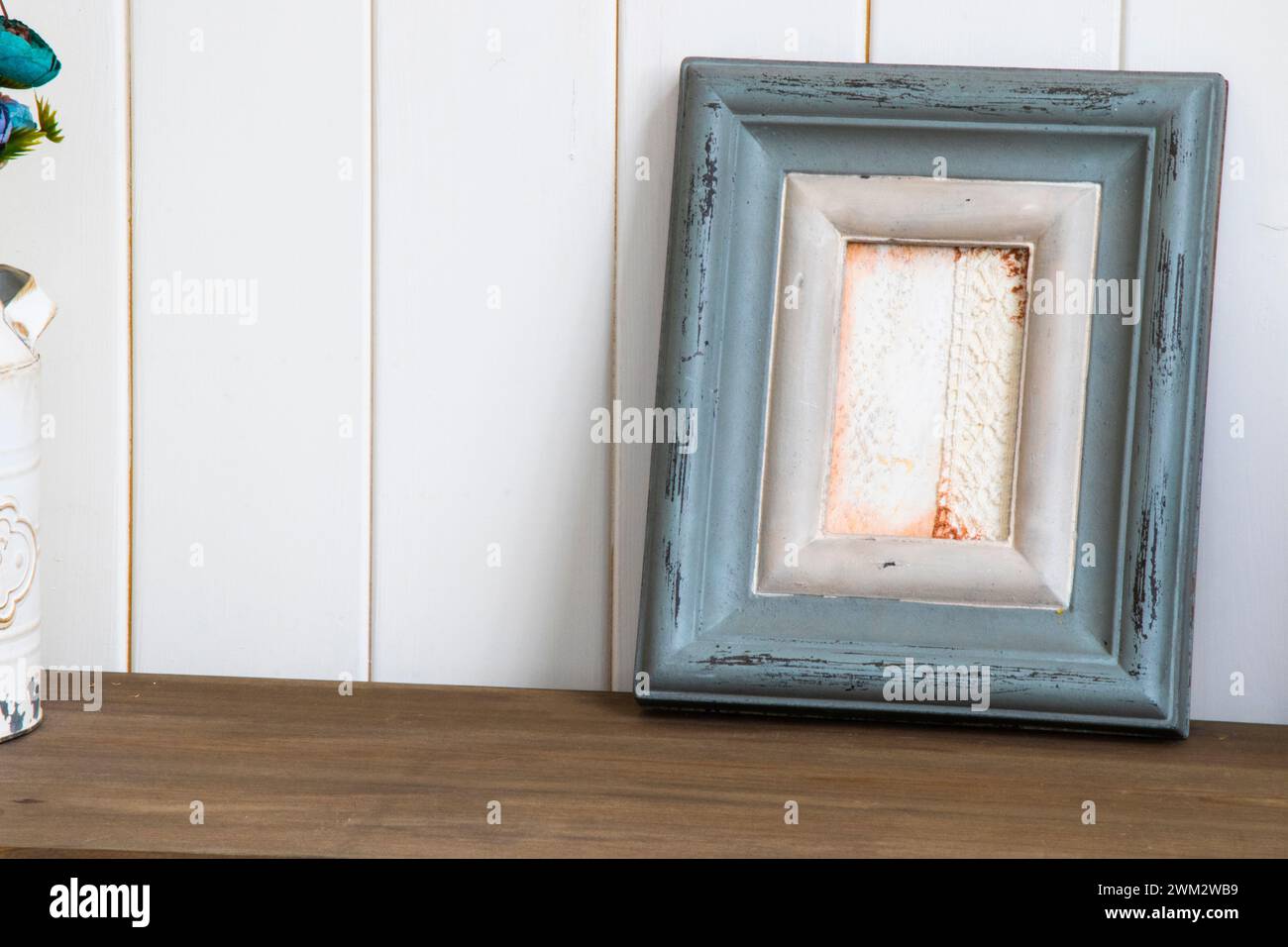 A tiny vase of flowers on wooden table next to picture frame Stock Photo