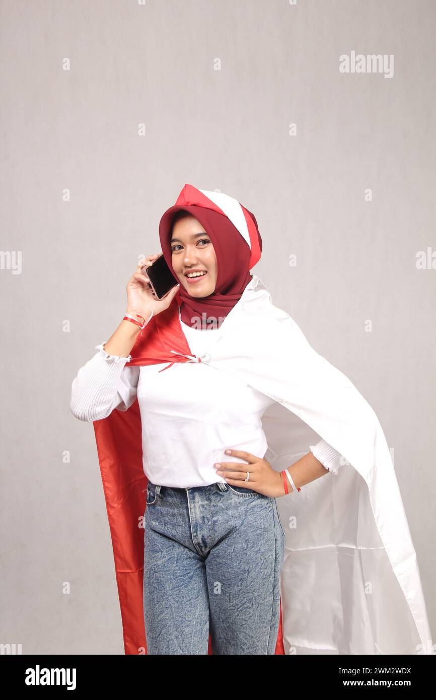 portrait of a woman wearing an Asian hijab wearing a white t-shirt playing her cellphone screen with her hands Stock Photo
