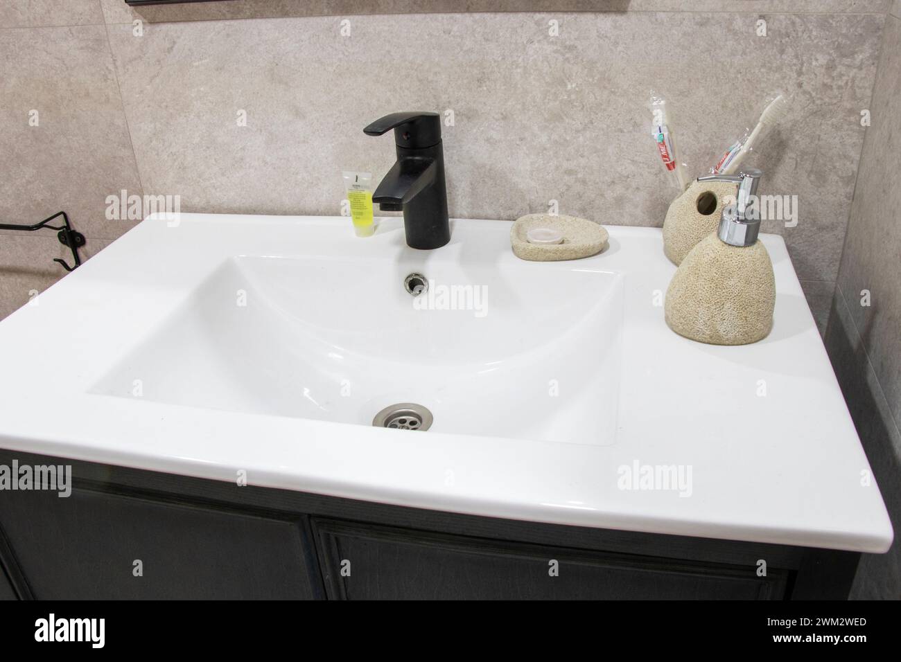 White sink with soap, sponges, and dispenser in a kitchen or bathroom Stock Photo