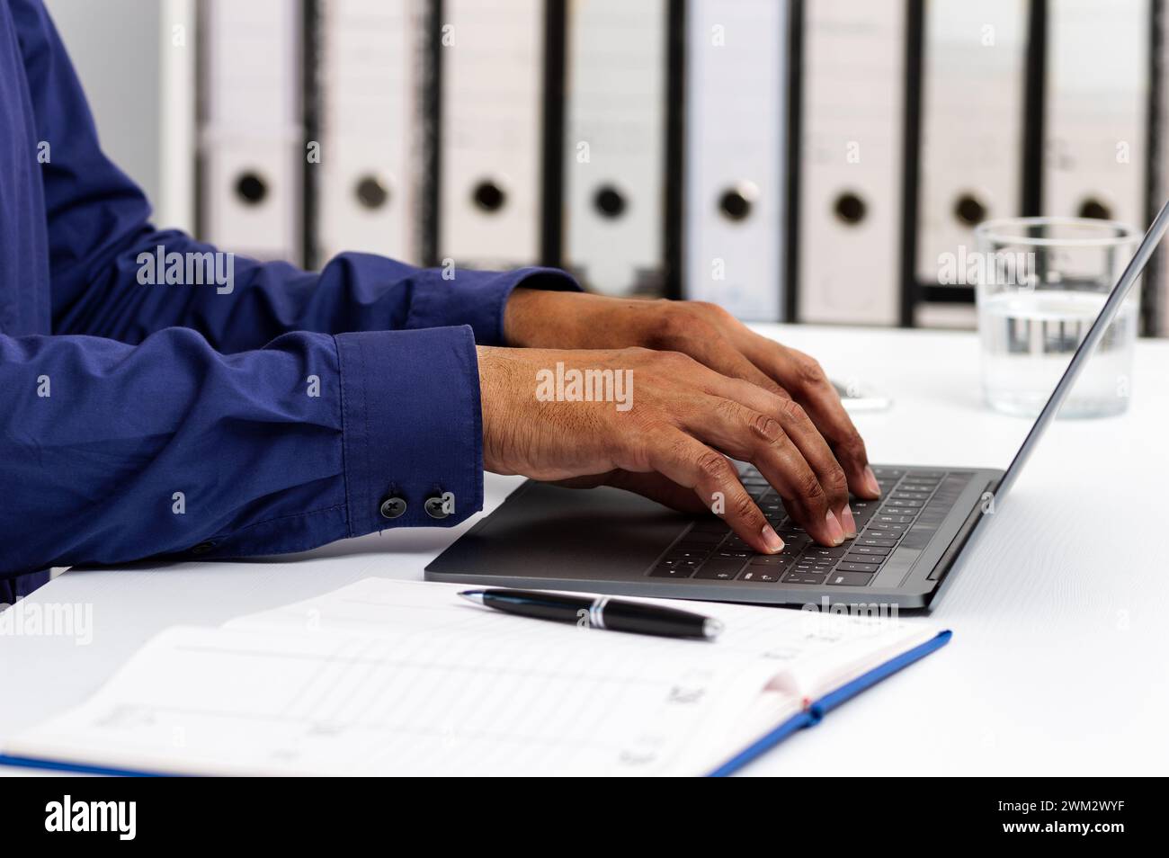 Closeup shot of an unrecognizable man using a laptop while working from office Stock Photo