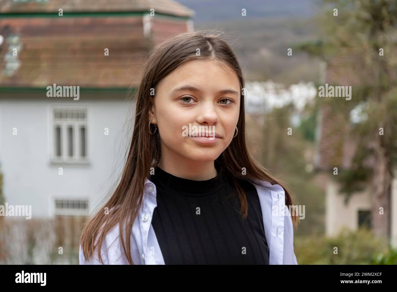 A teenage girl with long hair wearing a black shirt against a country landscape. Stock Photo