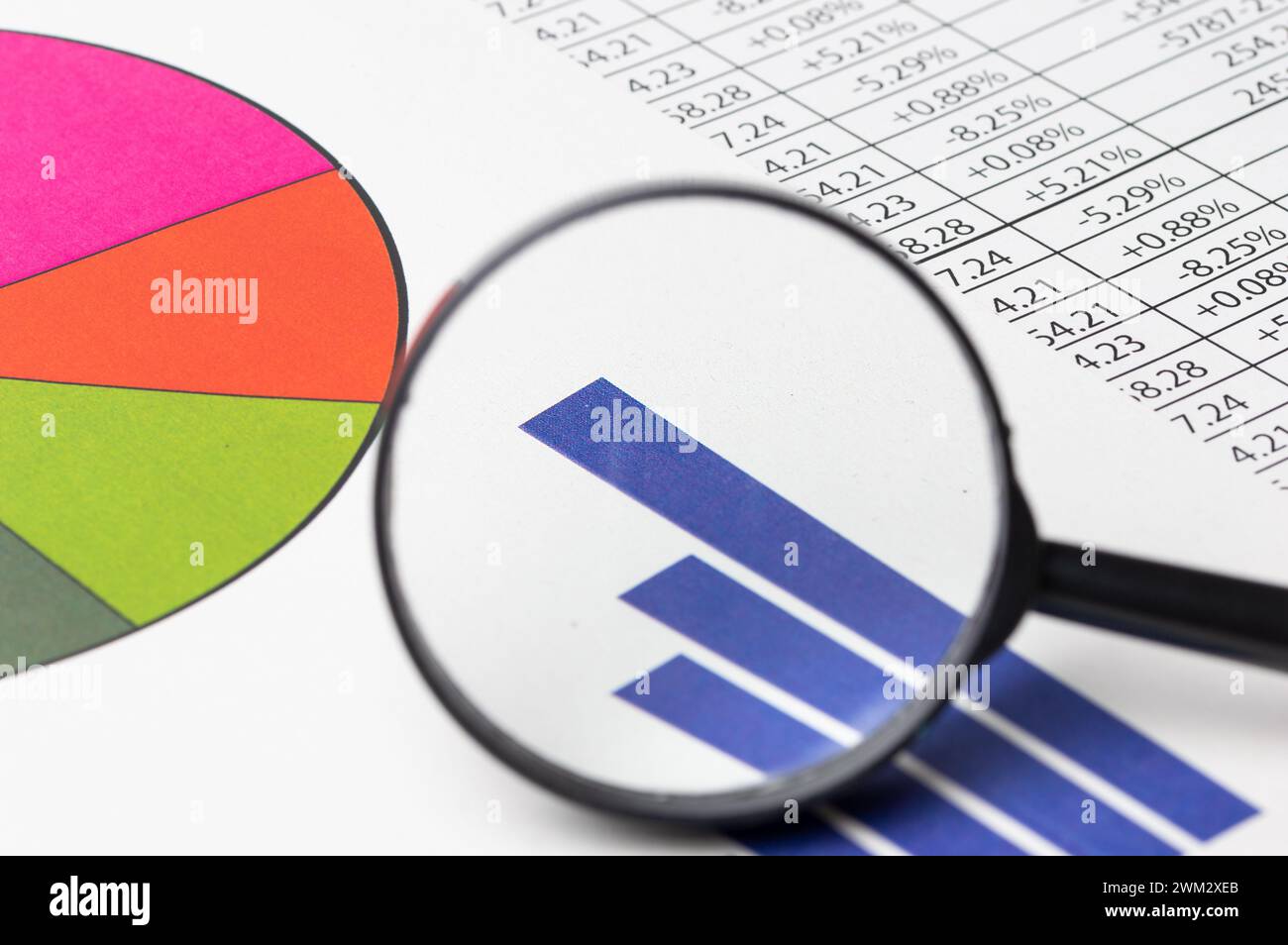 A magnifying glass on financial documents background, close-up Stock Photo
