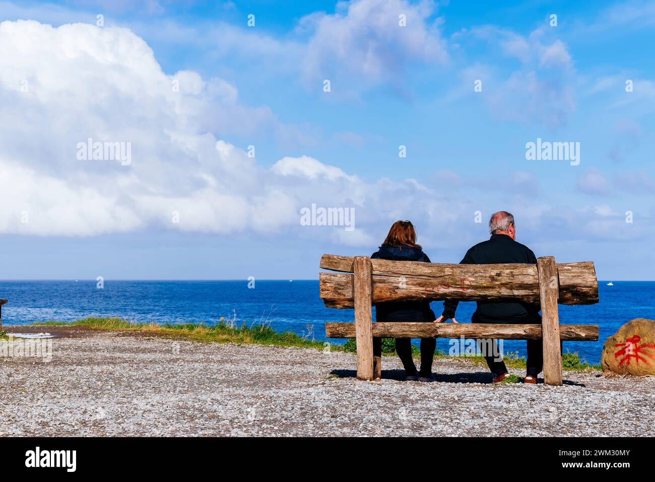 Couple sitting on a bench on top of the cliff. Zumaya, Guipúzcoa, País Vasco, Spain, Europe Stock Photo