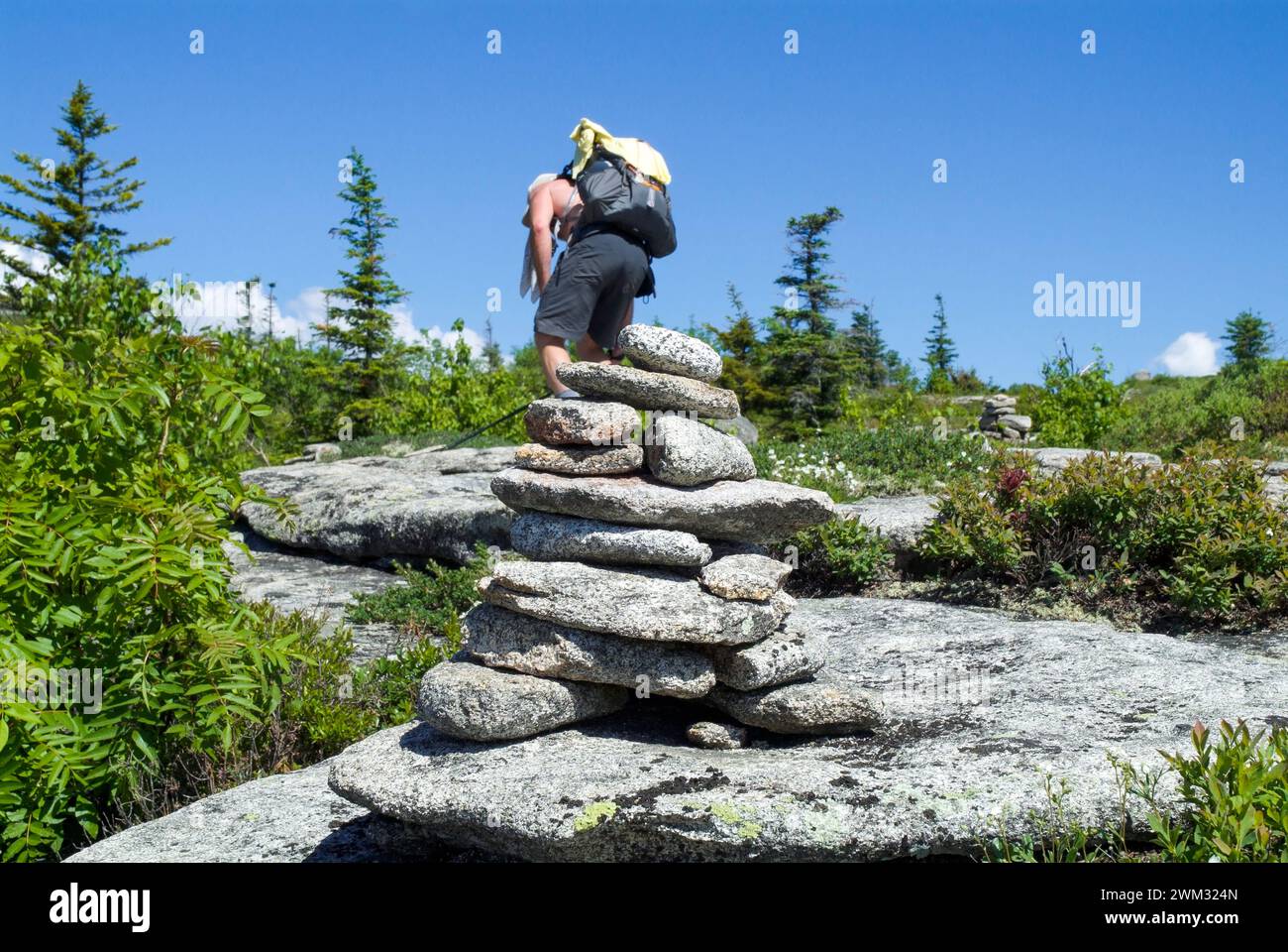 A Hiker passes a rock cairn on Baldface Knob Trail in the scenic landscape of the White Mountains, New Hampshire USA during the spring months. Stock Photo