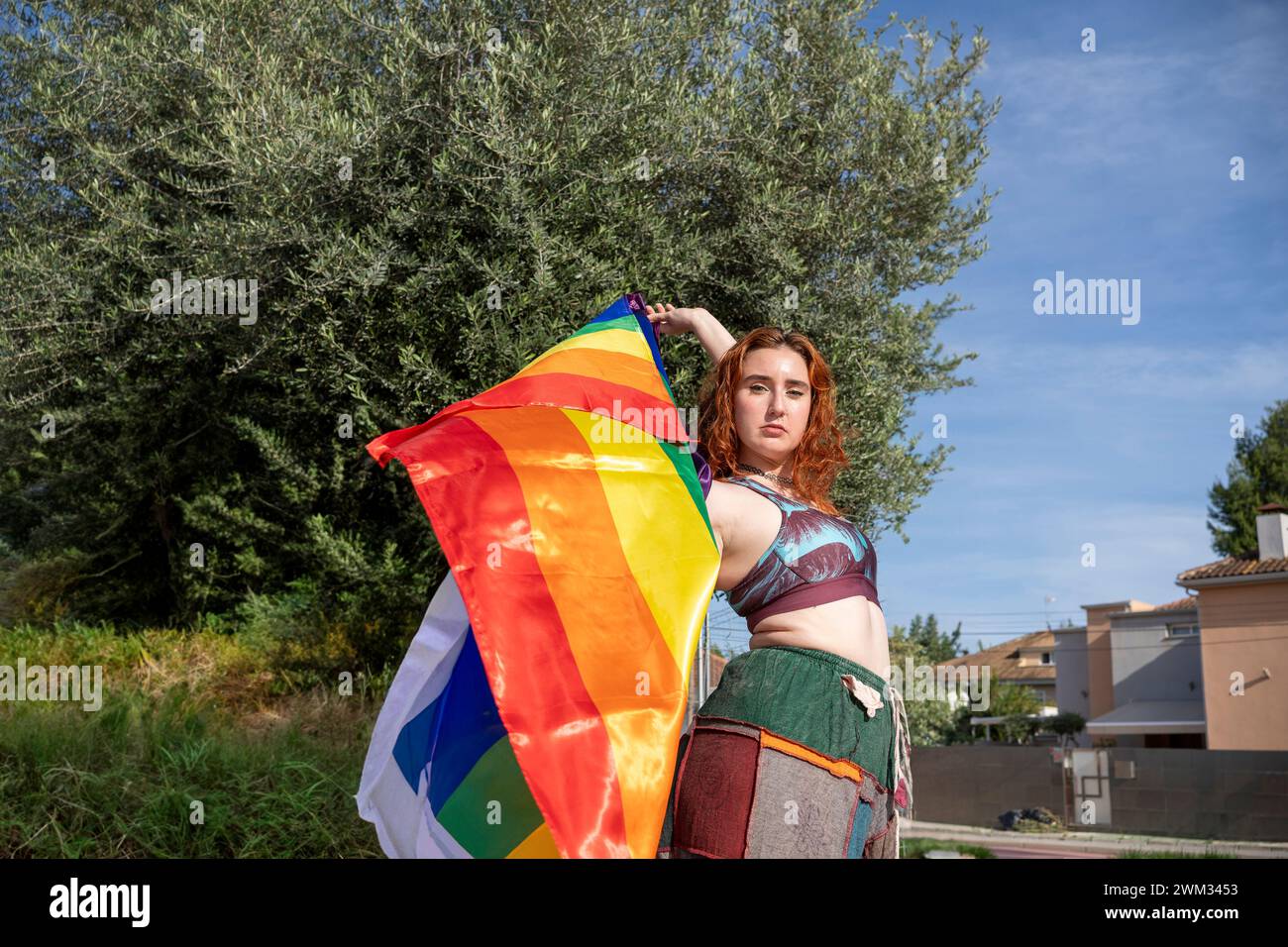 A Woman holding rainbow flag in front of building Stock Photo - Alamy