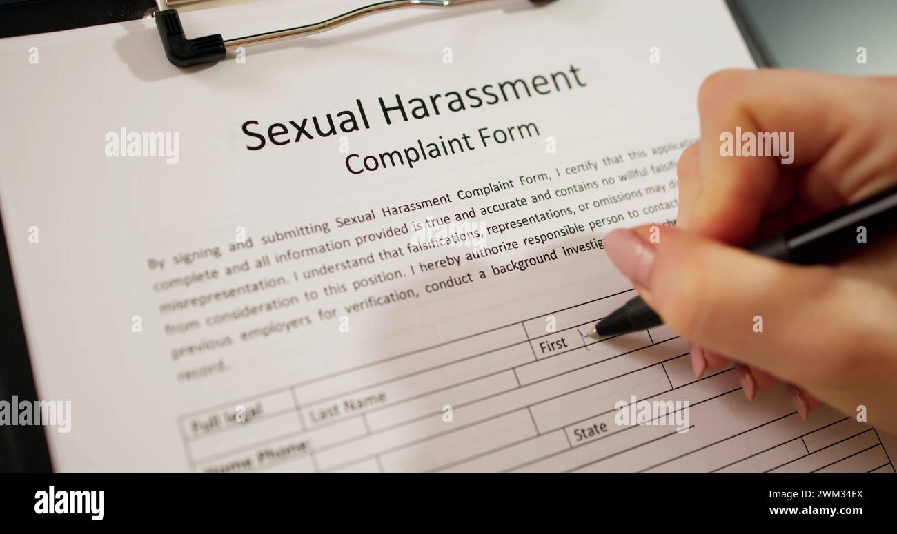 Close-up Of A Human Hand Filling Sexual Harassment Complaint Form With Pen Stock Photo