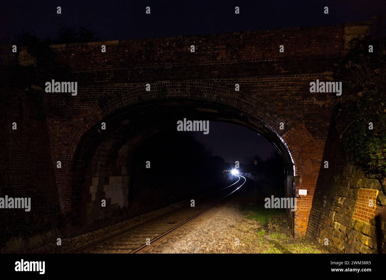 Train about to pass under a bridge at  Finstock on the Cotswolds railway line at Finstock, Oxfordshire, UK Stock Photo