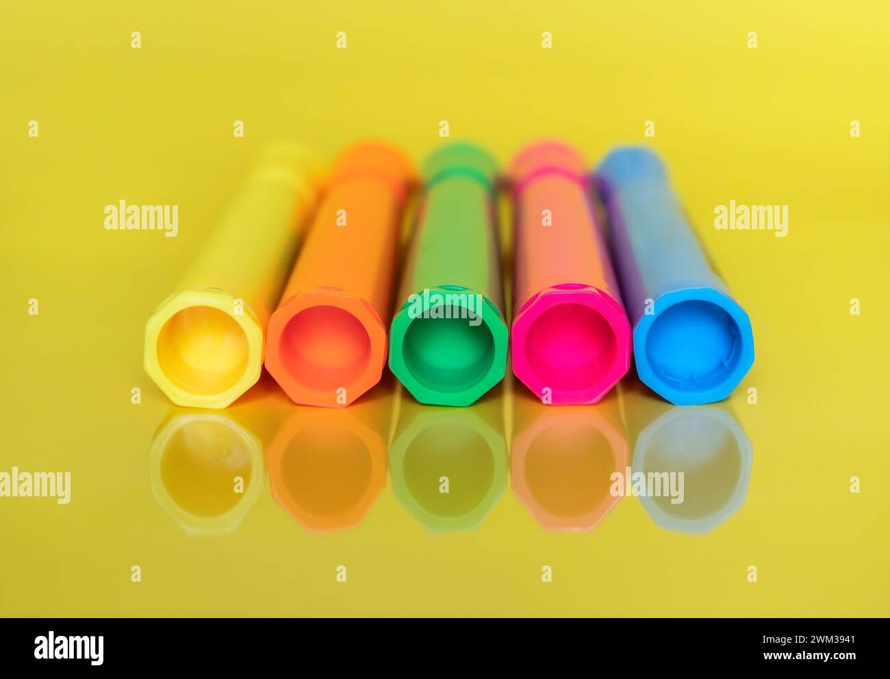 Coloured fluorescent highlighter marker pens on bright yellow background Stock Photo