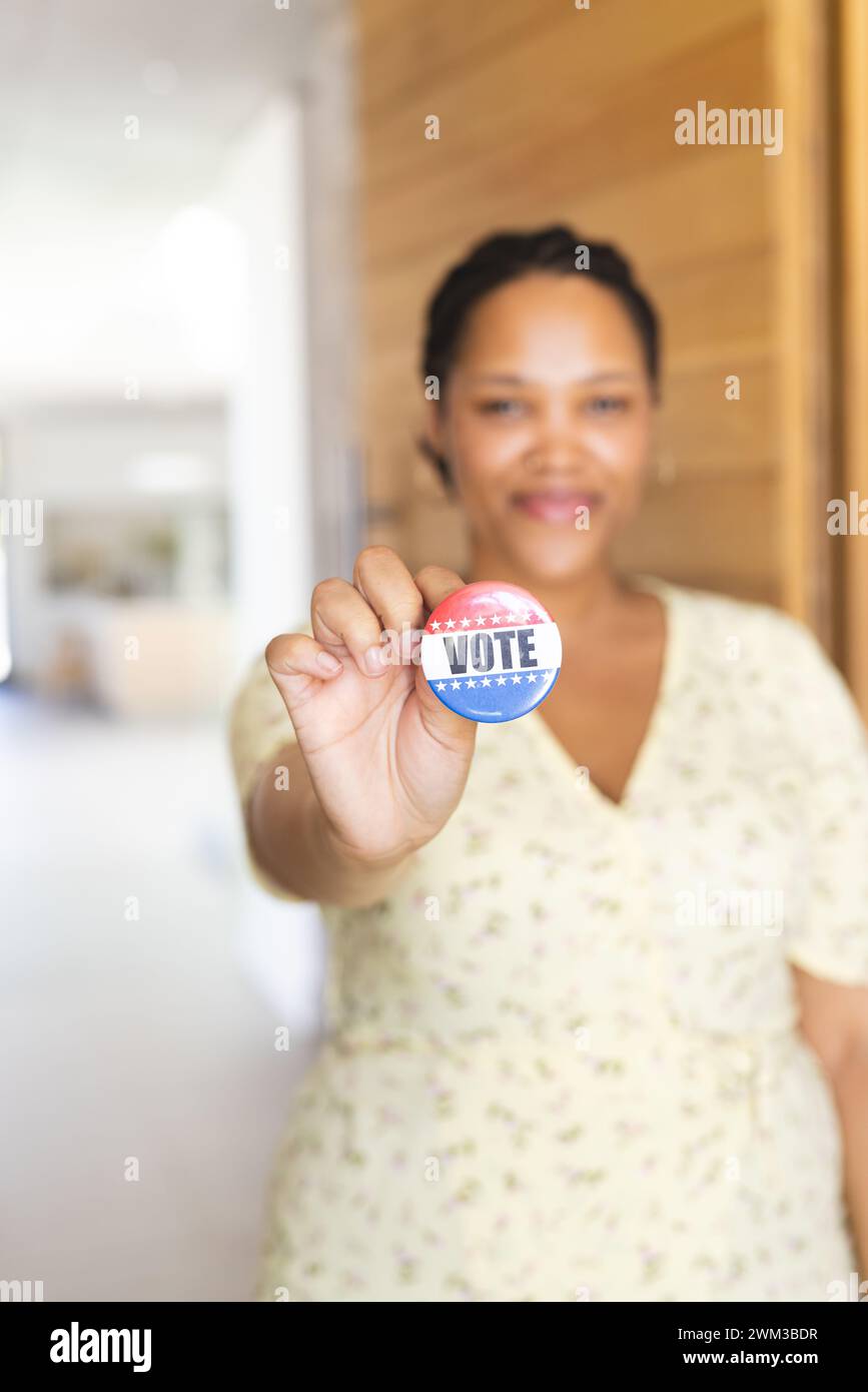 Young biracial woman holds a 'vote' badge, with copy space Stock Photo