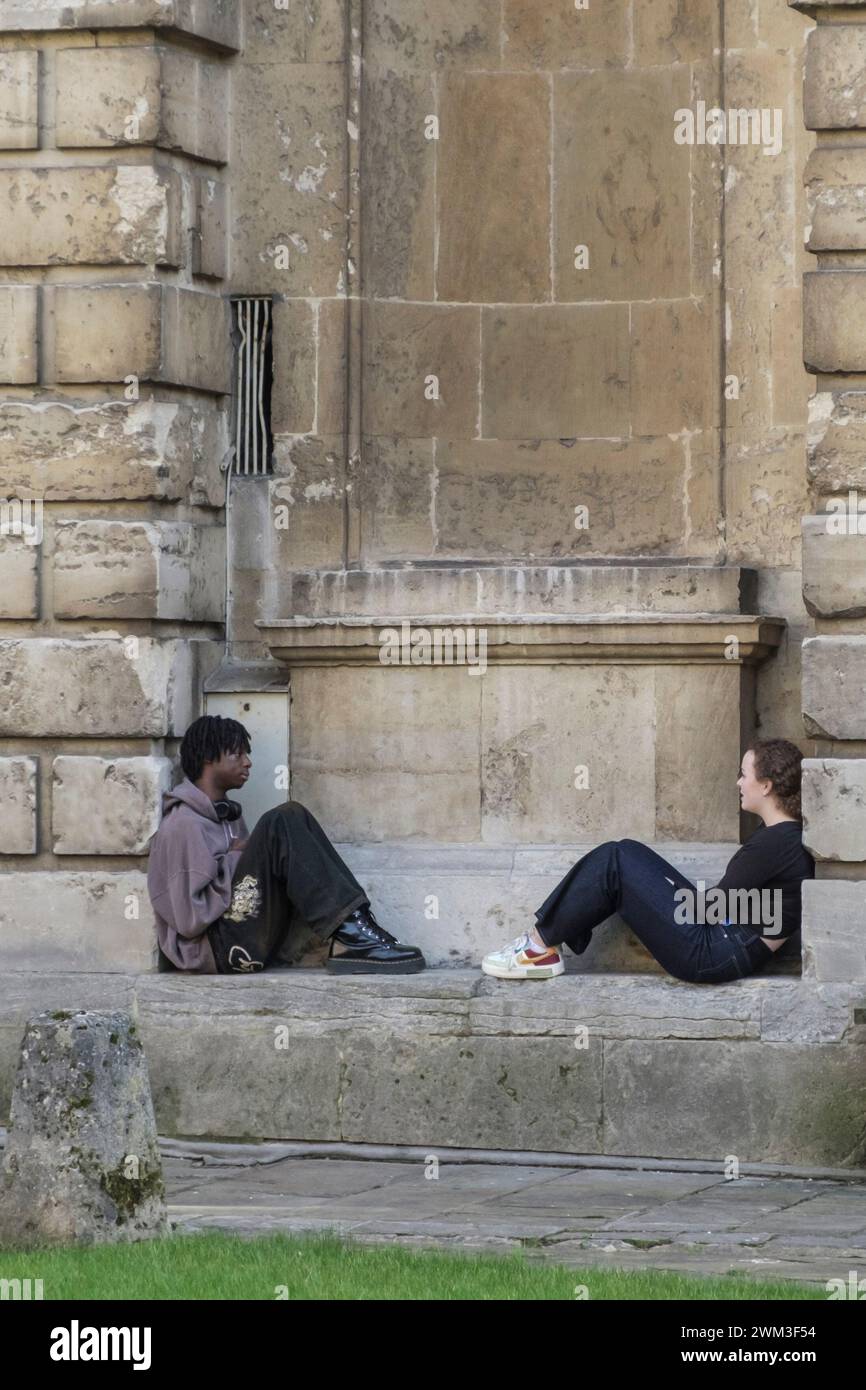 Around the University city of Oxford UK. Two youg people sat in the niches of Radcliffe Camera Stock Photo