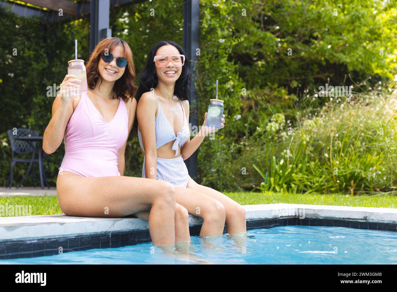 Two women enjoy a sunny day by the pool, with copy space Stock Photo