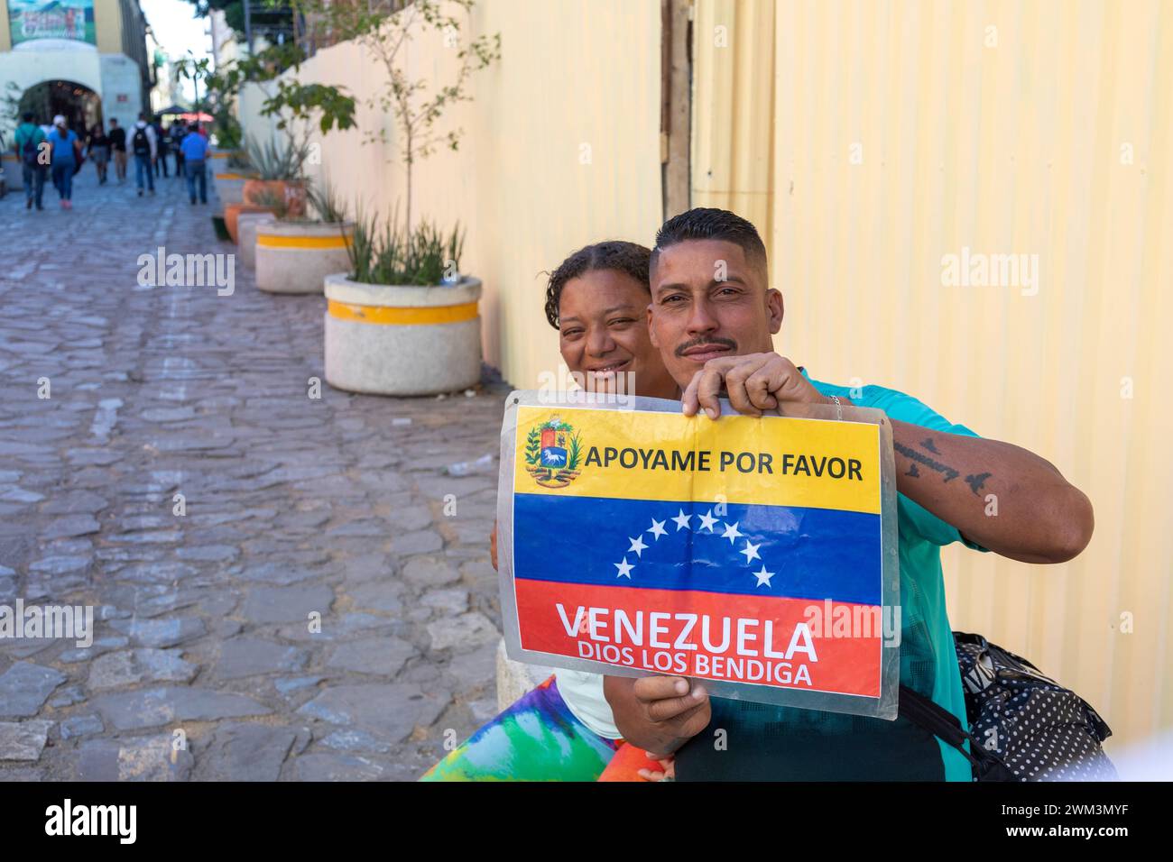 Oaxaca, Mexico - A man and a woman trying to make their way from Venezuela to the United States hold a sign asking for help. Stock Photo