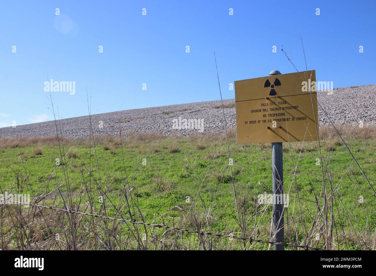 A “Uranium Mill Tailing Repository” and a “Radiation Warning” symbol on a sign along the perimeter fence at the Falls City disposal site near Karnes County, Texas, USA, on February 23, 2024. The Falls City disposal site contains 5.1 million cubic yards of contaminated material, with a total activity of 1,277 curries of radium- 226. The disposal site is located over the Eagle Ford Shale Geological Area, which is an active oil and gas producing region. Recently, the area has had 20 earthquakes of a magnitude 2.5 or or higher in a span of 30 days. (Photo by Carlos Kosienski/Sipa USA) Stock Photo