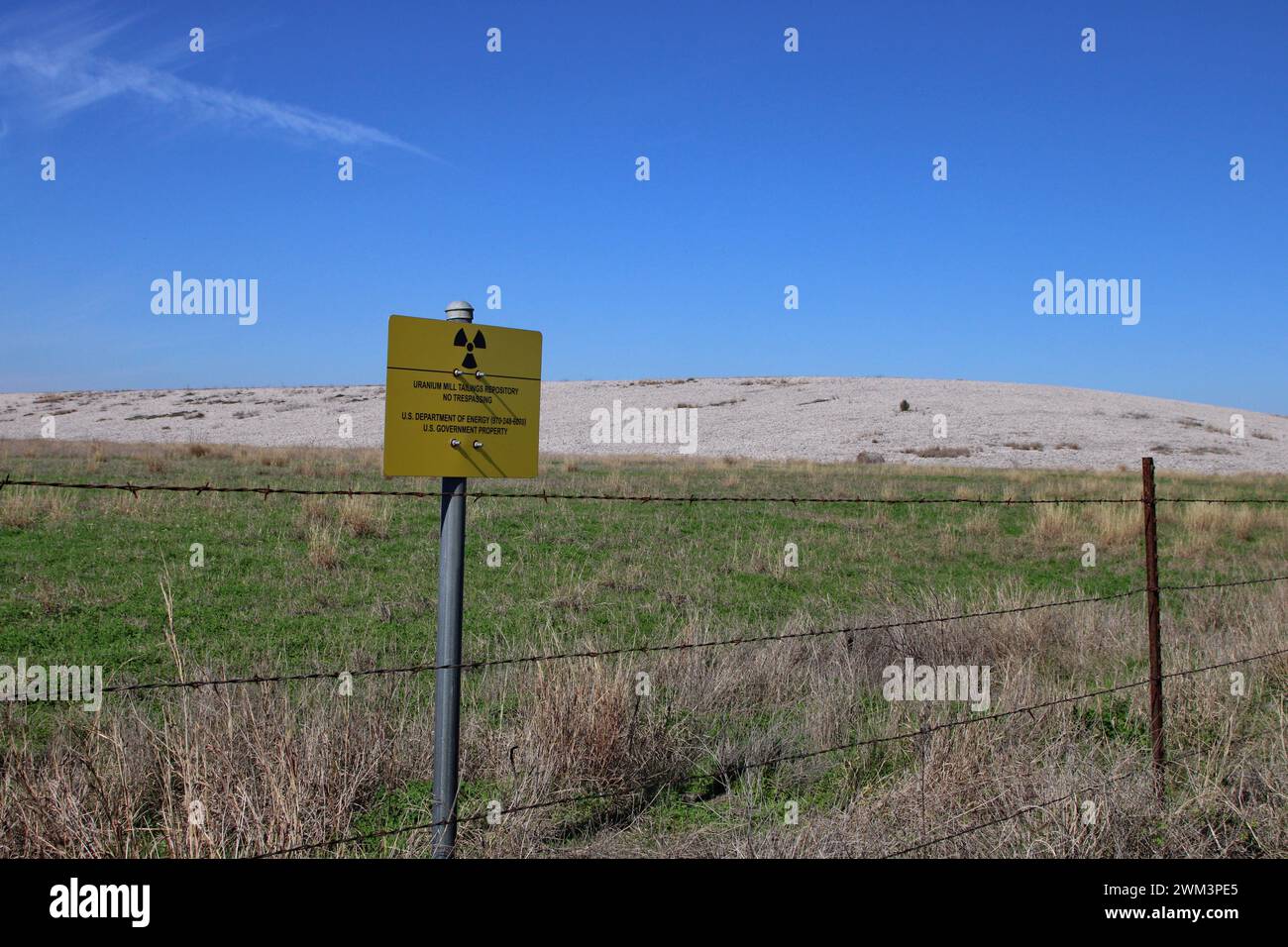 A “Uranium Mill Tailing Repository” and a “Radiation Warning” symbol on a sign along the perimeter fence at the Falls City disposal site near Karnes County, Texas, USA, on February 23, 2024. The Falls City disposal site contains 5.1 million cubic yards of contaminated material, with a total activity of 1,277 curries of radium- 226. The disposal site is located over the Eagle Ford Shale Geological Area, which is an active oil and gas producing region. Recently, the area has had 20 earthquakes of a magnitude 2.5 or or higher in a span of 30 days. (Photo by Carlos Kosienski/Sipa USA) Stock Photo