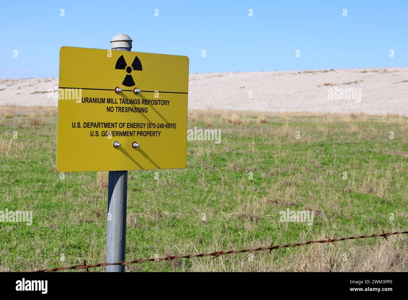 A “Uranium Mill Tailing Repository” and a “Radiation Warning” symbol on a sign along the perimeter fence at the Falls City disposal site near Karnes County, Texas, USA, on February 23, 2024. The Falls City disposal site contains 5.1 million cubic yards of contaminated material, with a total activity of 1,277 curries of radium- 226. The disposal site is located over the Eagle Ford Shale Geological Area, which is an active oil and gas producing region. Recently, the area has had 20 earthquakes of a magnitude 2.5 or or higher in a span of 30 days. (Photo by Carlos Kosienski/Sipa USA) Stock Photo