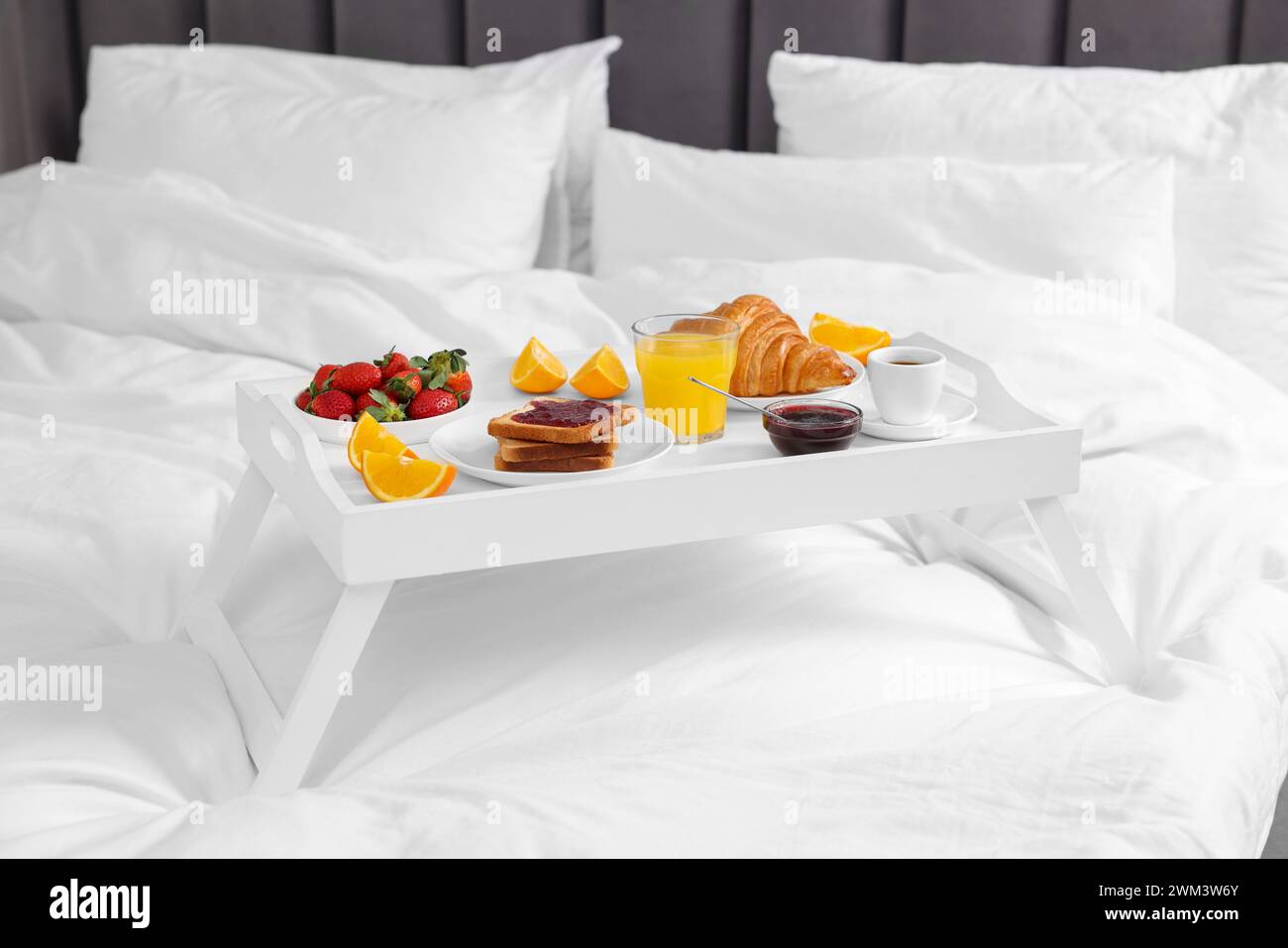 White tray with delicious breakfast on bed Stock Photo