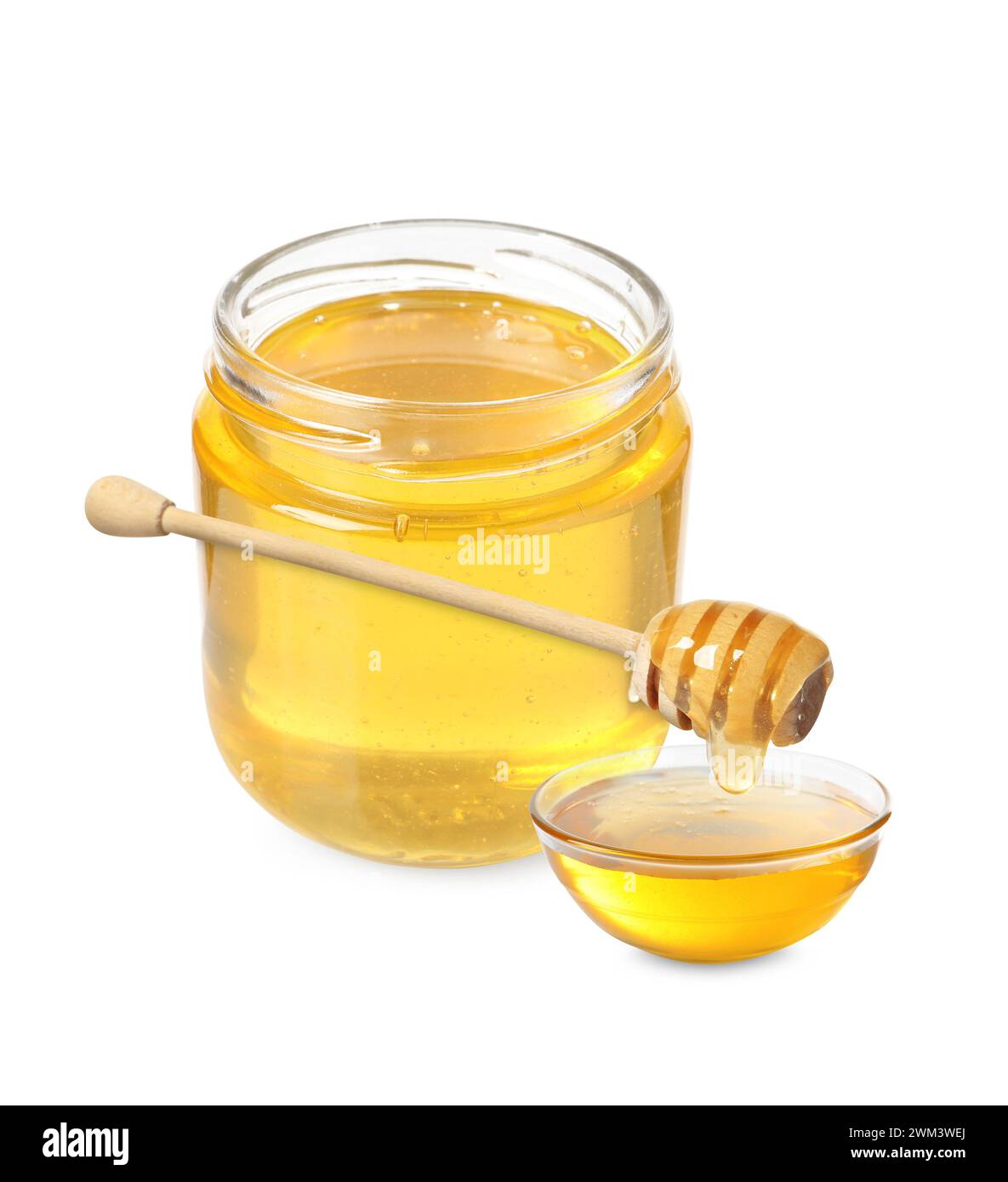 Natural honey dripping from dipper into glass bowl. Jar full of honey ...