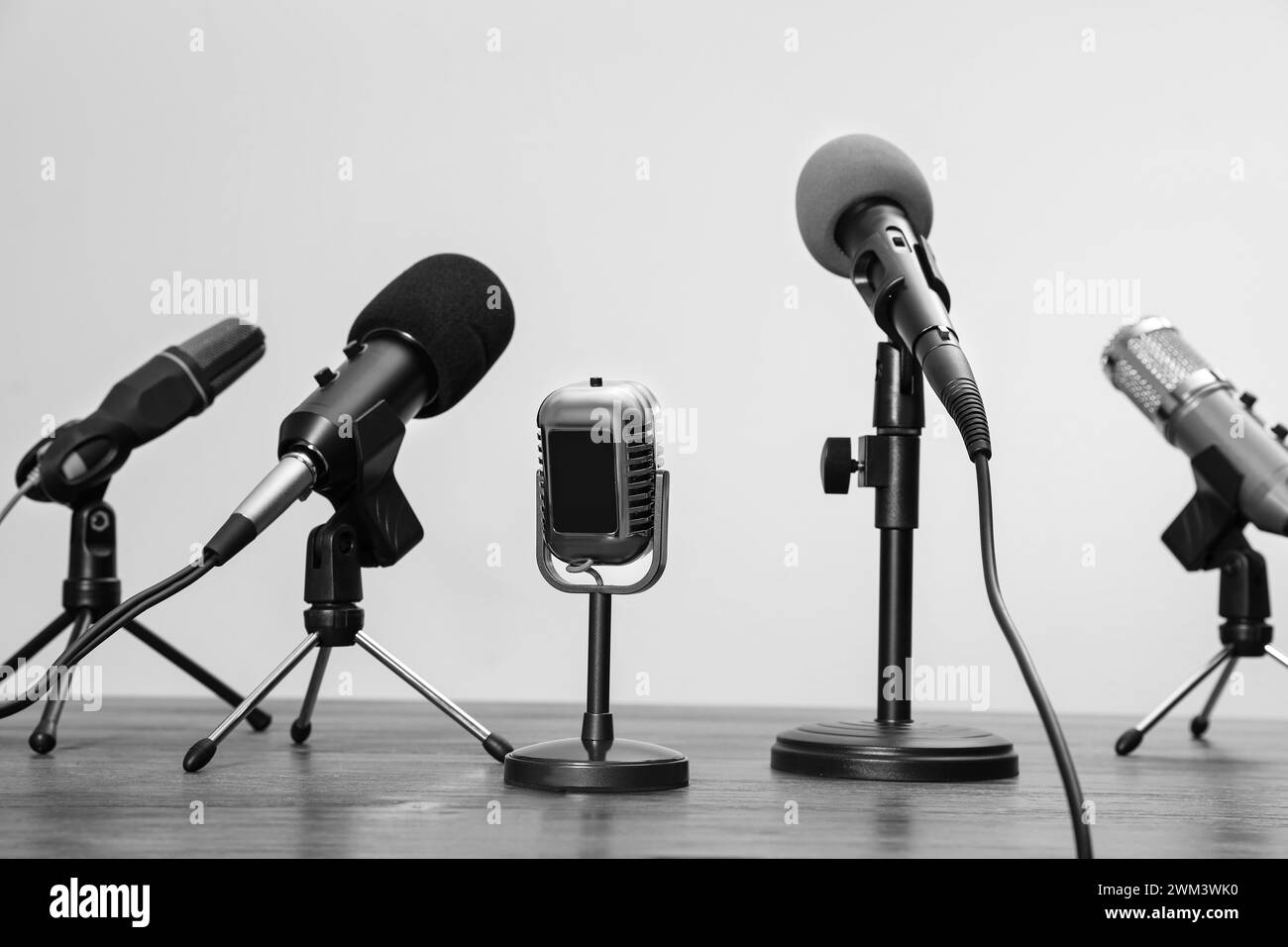 Journalist's equipment. Different microphones on wooden table. Black and white effect Stock Photo
